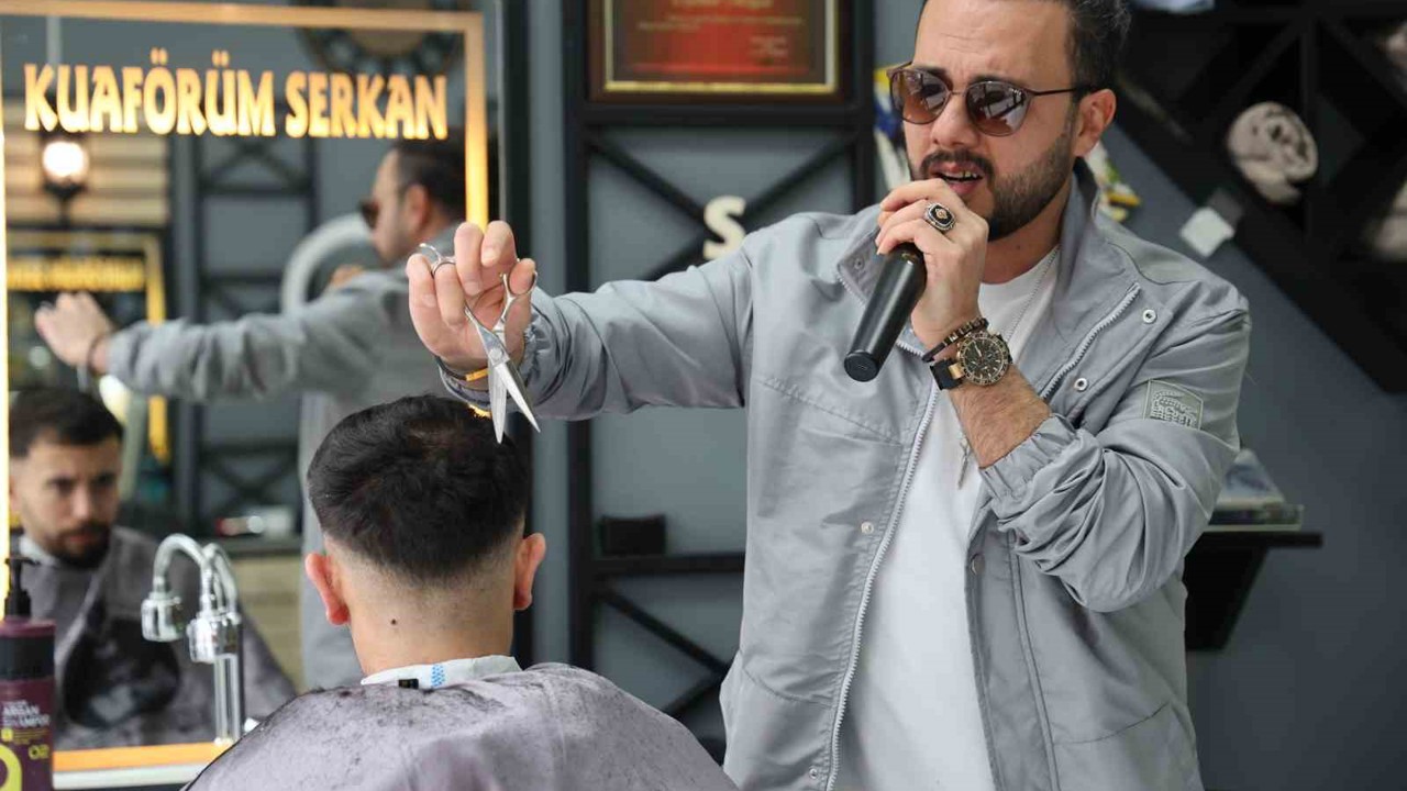 Bir elinde makas diğer elinde mikrofon
